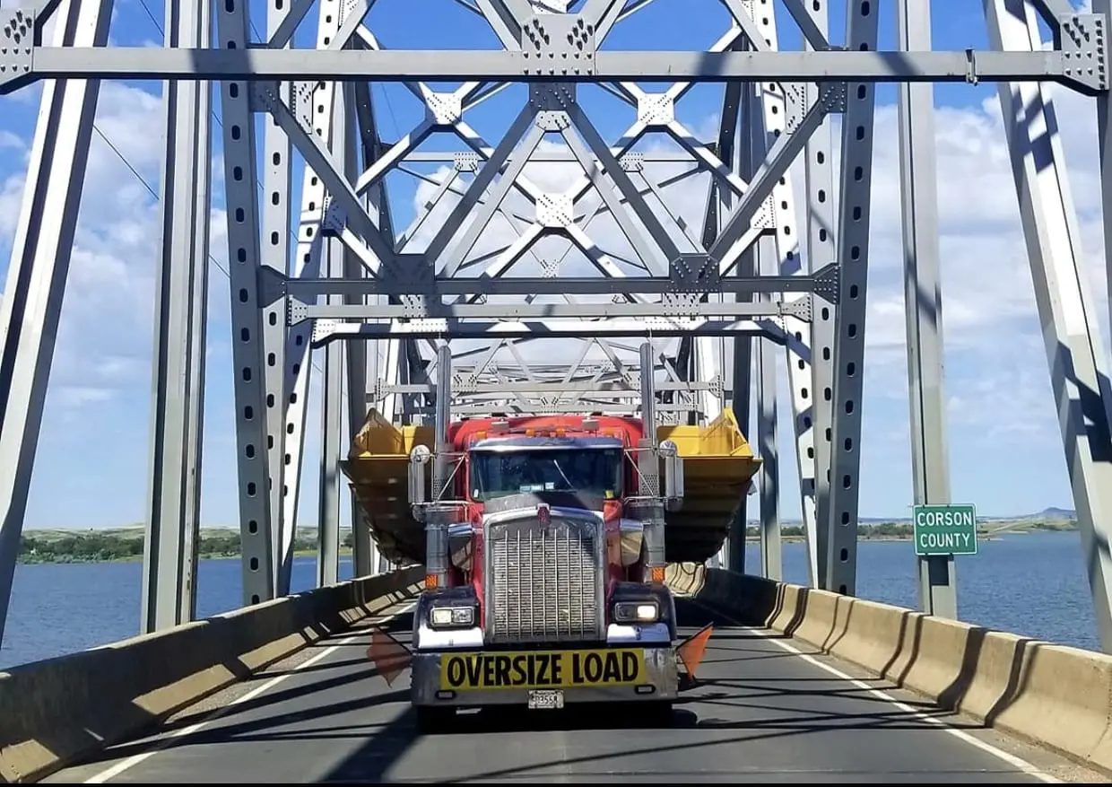 A semi truck driving across the bridge over water.
